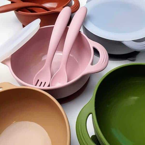 A set of colorful bowls with spoons and forks.