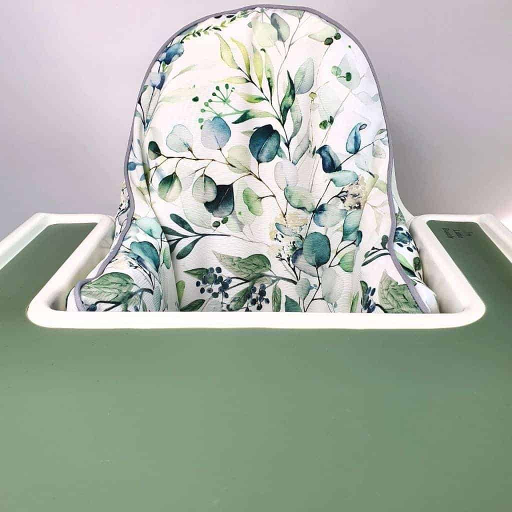 A green high chair with a floral seat cover. A green high chair with a floral seat cover.
