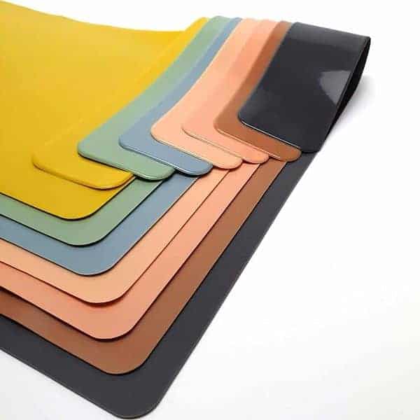 A stack of different colored rubber mats on a white surface.