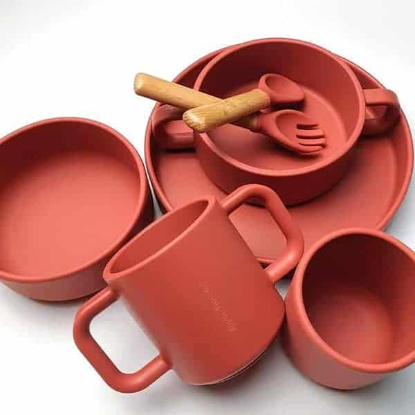A set of red dinnerware with wooden spoons and utensils.